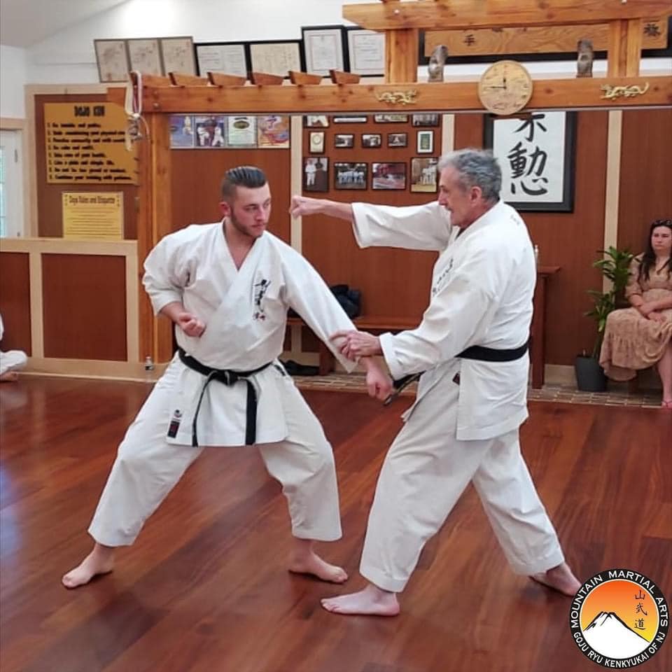 Two men in white uniforms practicing karate moves.
