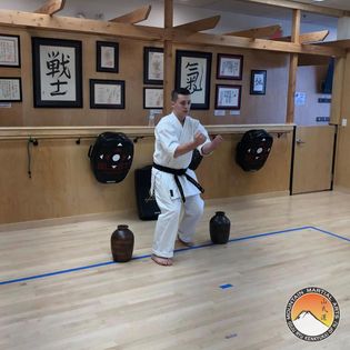A man in white shirt and black belt doing karate.