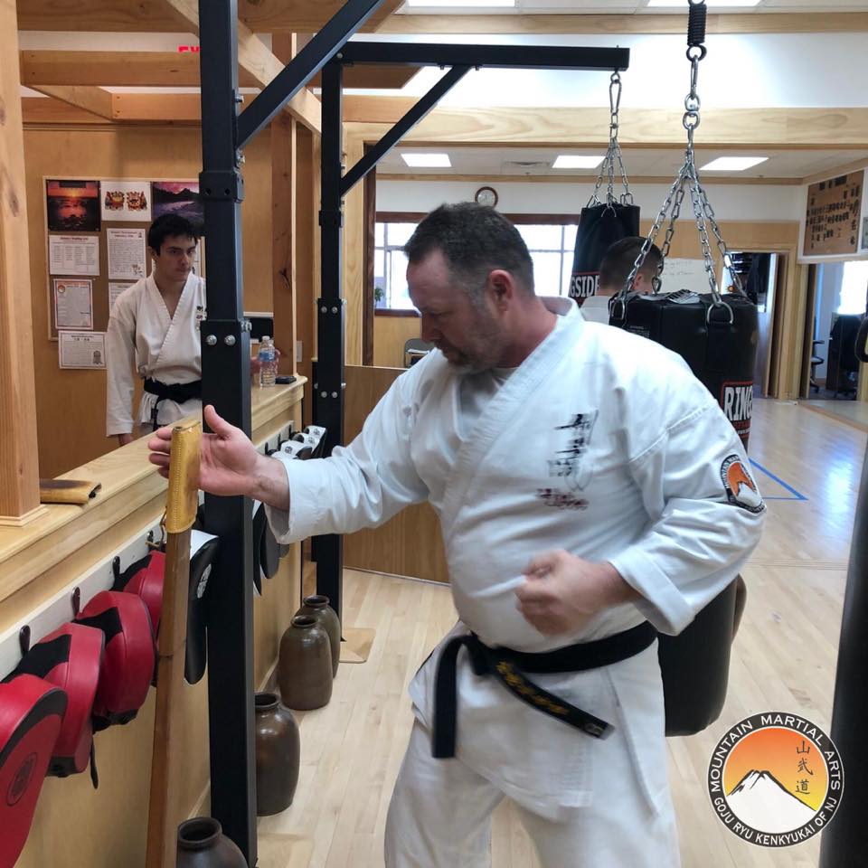 A man in white shirt and black belt doing karate.