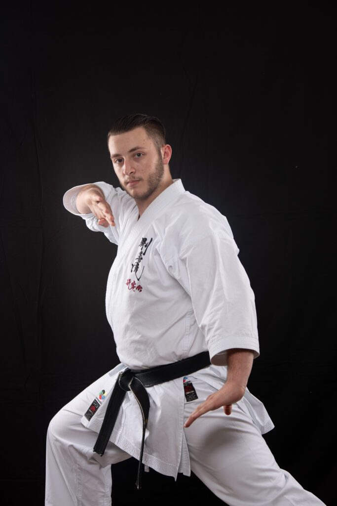 A man in white shirt and black belt doing karate.